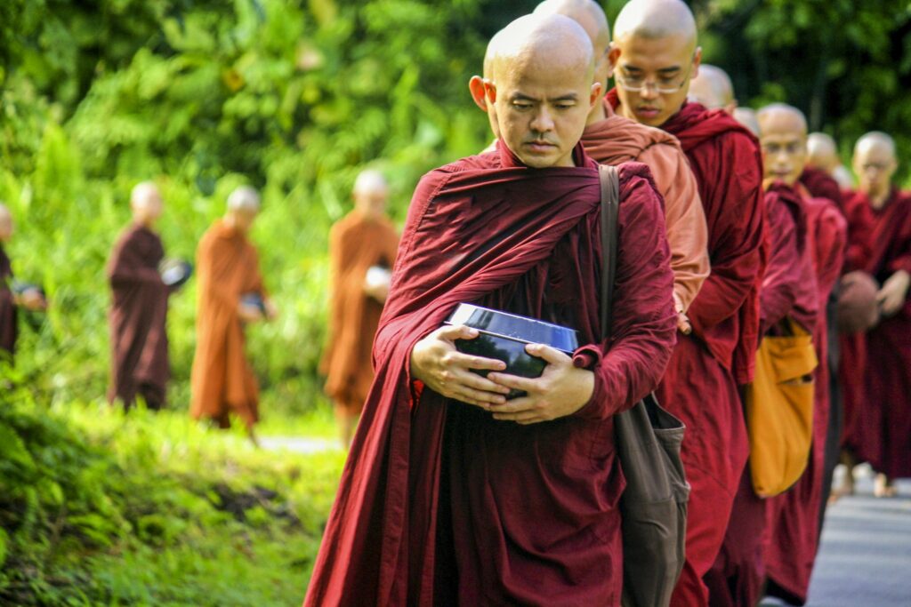 Buddhist monks in traditional maroon robes walking in a serene environment, representing the spiritual essence of Gompa in Itanagar, Arunachal Pradesh