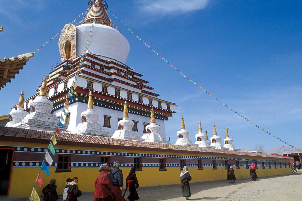 A Buddhist monastery with stupas, prayer flags, and traditional Tibetan architecture.